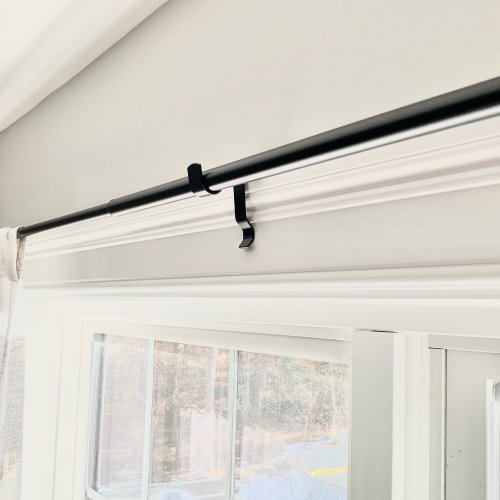 Black Kwik-Hang no-drill center support curtain bracket installed on a window